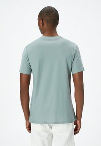 Lys teal kortærmet t-shirt med rund halshulm og en blød tekstur, der har et afslappet fit og sømløs skulderdesign.
