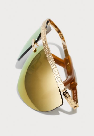 Gold-framed sunglasses with green and brown gradient lenses, featuring logo accents on the arms and a sleek, modern design.