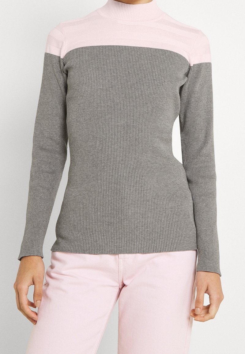 Szary sweter typu golf z prążkowanego materiału, z różową poziomą paską na górnej części klatki piersiowej. Długie rękawy, dopasowany krój, miękka tekstura.