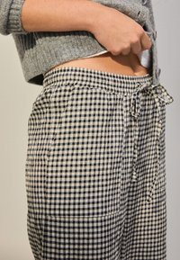 Bukser med sort-hvidt gingham-mønster, elastisk talje og snøre, med afslappet pasform og blød stoftekstur.