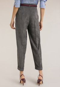 Graue, gestreifte, hochtaillierte Hose mit strukturierter Oberfläche, mit aufgekrempelten Säumen und einem burgunderroten Gürtel. Rückansicht, gezeigt mit hochhackigen Schuhen.