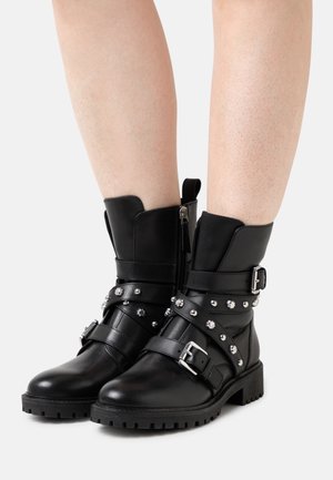 Sorte læderankelstøvler med sølvnitter og spænder. Har en sidesyning, teksturerede remdetaljer og en robust sål.
