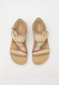Lys beige sandaler med stoffremmer og en fargerik flettet dekorasjon. Flat design med en subtil tekstur og justerbar spenne.