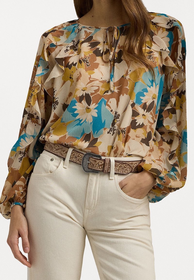 Hedvábná blůza s květinovým vzorem v béžových, hnědých a modrých odstínech; má nařasený výstřih s tkaničkou a dlouhé puffované rukávy.