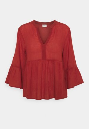 Blouse rouge ample avec manches évasées trois-quarts, encolure en V avec bordure et détail taille froncée.