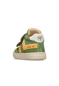 Zapatilla alta verde de ante con acentos amarillos, tiras de Velcro, lengüeta blanca y suela texturizada. Número de modelo "NTR-74" visible.