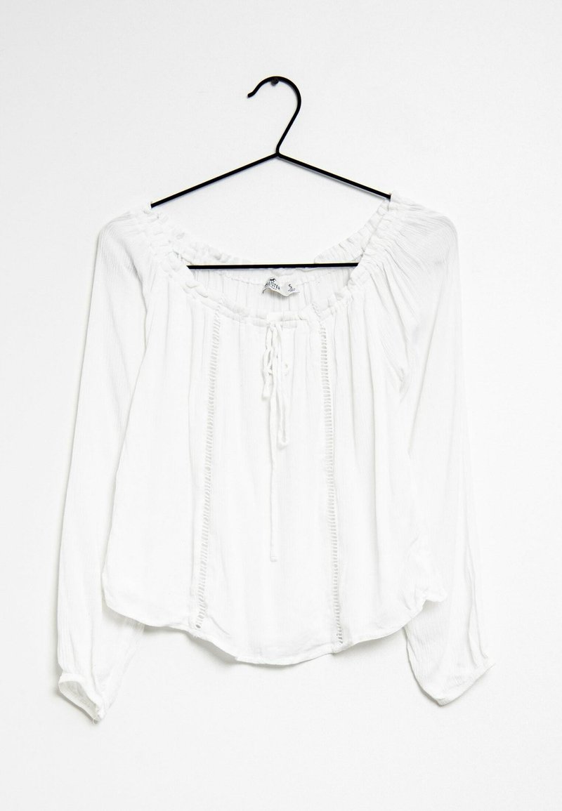 Blusa bianca a maniche lunghe con scollatura rotonda arricciata, dettaglio con fiocco, tessuto texturizzato e pieghe verticali lungo la parte anteriore.