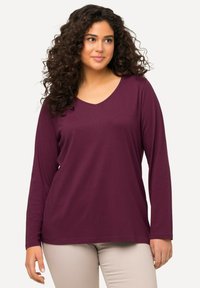 Halenka s dlouhým rukávem a výst�řihem do V v tmavě burgundské barvě, vyrobená z jemné látky, s volným střihem a hladkou texturou. Jednoduchý design bez vzorů nebo akcentů.