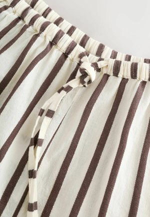 Gestreepte stof met een elastische tailleband en een gestrikte trekkoord. Kleuren zijn onder andere crème en bruin, met verticale strepen en een zachte textuur.