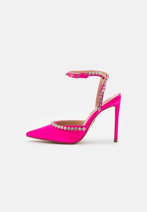 Chaussure à talon haut pointue rose vif avec bride à la cheville et ornements de strass ronds transparents le long des bords et de la bride.