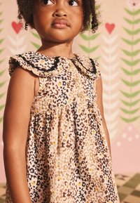 Leoparda raksta kleita pasteļtoņos ar volānu apkakli, pogām priekšpusē un savilktu svārku daļu. Materiāls izskatās teksturēts ar maigu apdari.