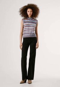 Top de malha sem mangas com riscas horizontais multicoloridas em azul, rosa e branco. Combinado com calças pretas de cintura alta e boca de sino.