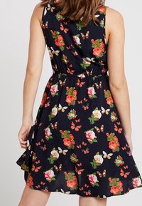 Květinové šaty s tmavě námořnickým pozadím, zdobené živými růžemi a motýly, bez rukávů, s elastickým pasem a rozšířeným lemem.