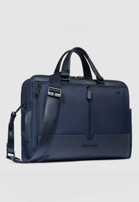 Sacoche d'ordinateur bleu marine en tissu texturé et cuir lisse, dotée de deux poignées supérieures, d'une bandoulière réglable et de plusieurs poches zippées.