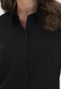 Black button-up shirt featuring a classic collar, soft texture, and a streamlined fit, with six matching buttons down the front.