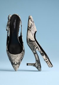 Escarpins à bout pointu avec un motif serpent noir et blanc. Présentent des côtés découpés et un talon stiletto élancé. Intérieur noir lisse.