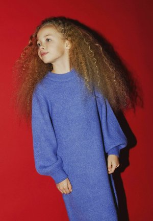 Langärmliges, blaues Strickkleid mit hohem Kragen und gerippten Bündchen. Der Hintergrund hat eine einheitliche rote Farbe. Die Textur wirkt weich und gemütlich.