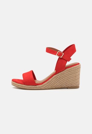 Rode nubuck sleehak sandalen met enkelband en gesp, met een gevlochten touwzool op een witte achtergrond.