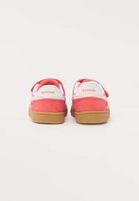 Baskets Reebok avec un dessus rose, des accents blancs et une semelle en gomme. Elles sont dotées d'une sangle velcro et d'un col rembourré pour plus de confort.