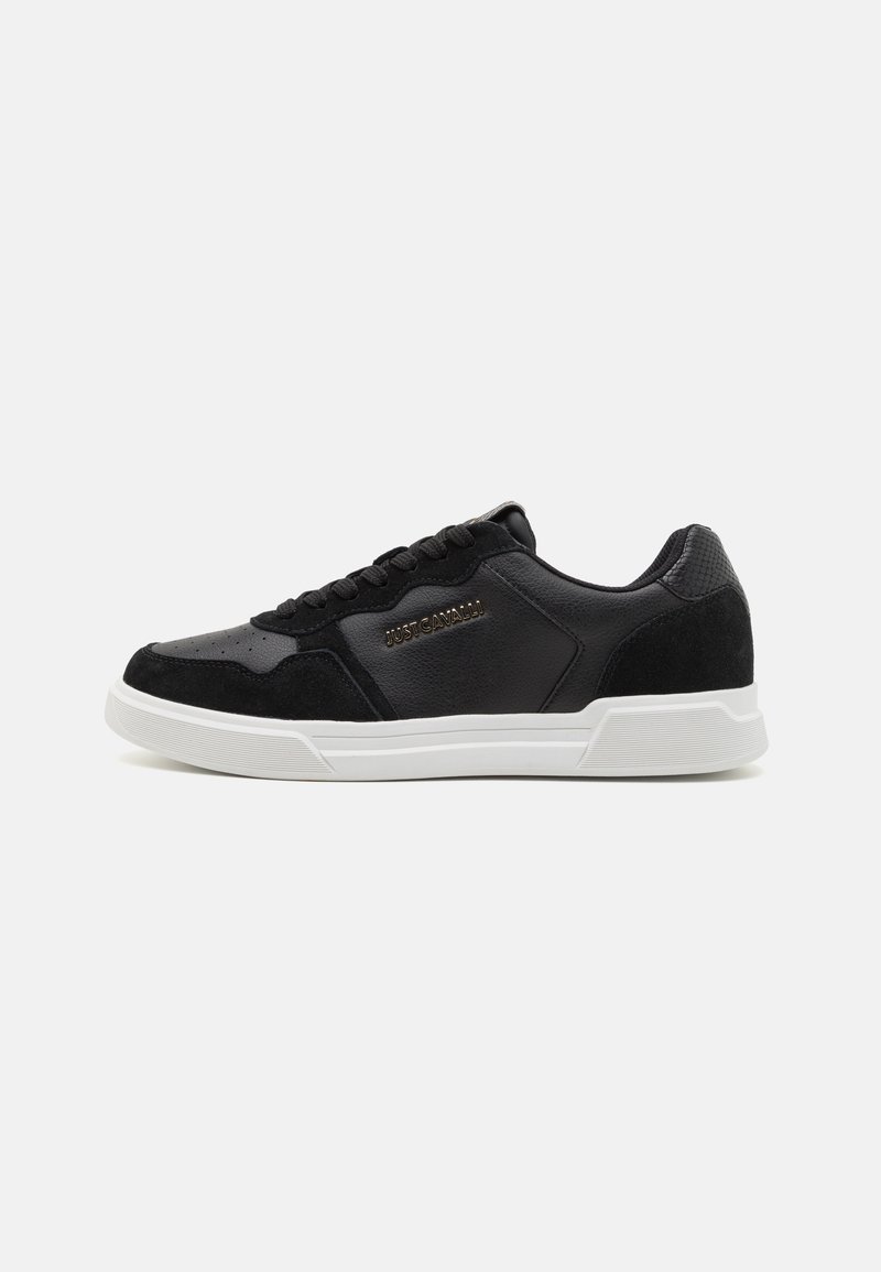 Baskets noires en mélange de cuir et de daim, avec un design épuré, semelle en caoutchouc blanc et détail logo doré sur le côté.