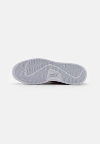 Puma sneaker buitenzool met een witte rubberen zool, een visgraatpatroon, logo-accent en een gestructureerd oppervlak voor grip.