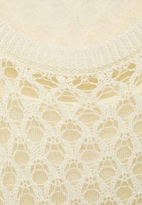 Ivory knitted sweater featuring a textured lace pattern with diamond shapes and a ribbed neckline. Soft, lightweight fabric.