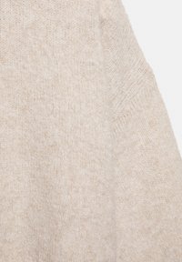 Bézs kötött pulóver lágy textúrával és laza szabással. Kerek nyakkivágással és enyhén eresztett vállakkal rendelkezik a kényelmes, lezser megjelenés érdekében.