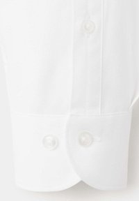 Poignet de chemise blanche à manches longues avec deux boutons nacrés et une patte de boutonnage verticale au-dessus du poignet sur un fond clair.
