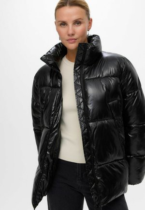 Juodas, blizgantis pūkinis švarkas su aukštu apykakle ir užtrauktuku. Savybės – siuvinėti intarpai ir minkštas, lygus paviršius. Dėvimas ant šviesios palaidinės.