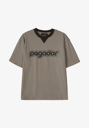 Rövid ujjú, laza szabású pamut póló taupe színben, barna V-kivágással és fekete "pegador" logóval a mellkason.