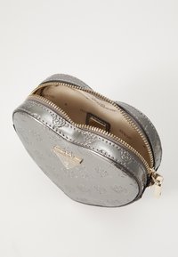Borsa a forma di cuore in argento con motivo a logo in rilievo, zip dorata e dettagli in pelle; l'interno presenta una fodera color crema.