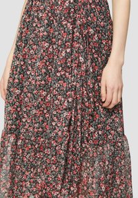 Robe maxi en tissu noir avec un motif floral ; présente des volants froncés et une texture légère et translucide ; design long et fluide.