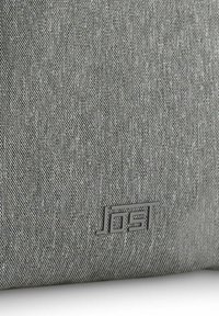 Graue Stofftasche mit strukturierter Oberfläche und einem dezenten Muster. Verfügt über ein elegantes schwarzes Logo-Element in der unteren Ecke.