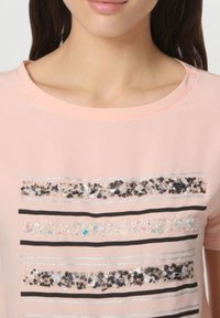 Top de manga corta rosa con rayas horizontales de lentejuelas y líneas negras; escote redondo, textura suave y un sutil brillo.