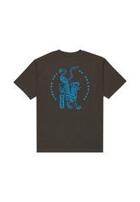 Donkere bruine t-shirt met een blauwe afbeelding van een tijger en de tekst "DE BALANS VAN TEGENSTELLINGEN" in een cirkelvormige opstelling. Korte mouwen.
