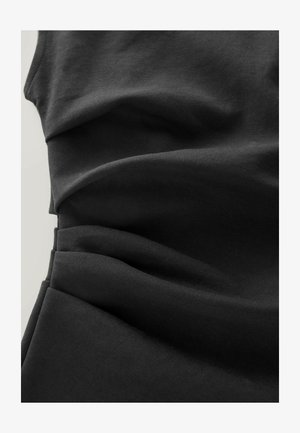 Must mustriline, mille pehme tekstuur ja rippuvate voldidega. Materjal näib kerge ja veniv, ideaalne keha järgi istuvate disainide jaoks.