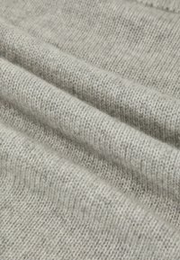 Tessuto lavorato a maglia grigio chiaro con una texture liscia, caratterizzato da punti fini e distribuiti uniformemente e da leggere venature in una tonalità leggermente più scura.