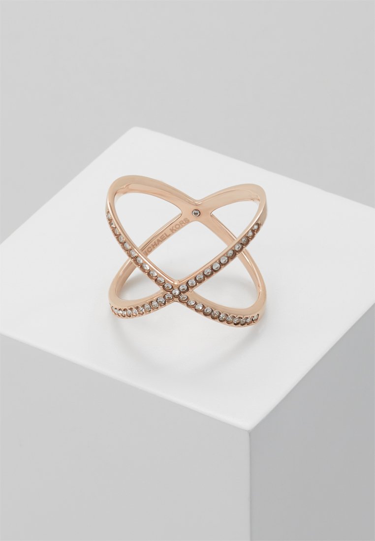Roze gouden ring met een kruisende X-ontwerp, versierd met heldere stenen langs één band en een gladde textuur, gepresenteerd op een witte display.