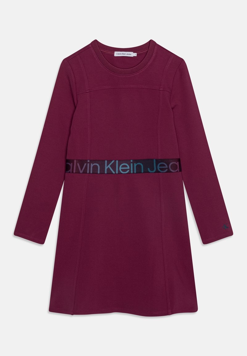 Abito color amaranto a maniche lunghe con scollo rotondo, caratterizzato da una fascia in vita testurizzata a contrasto con il logo "Calvin Klein Jeans". Tessuto liscio.