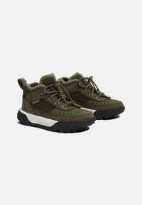 Chaussures de randonnée vertes en matériaux mesh et daim, dotées d'œillets renforcés, de lacets et de semelles en caoutchouc texturé pour une meilleure adhérence.