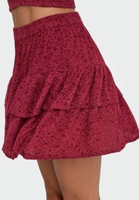 Rode bloemenprint rok met een gestructureerde stof, aansluitende taille en gelaagde ruches, die een lichte en vloeiende uitstraling benadrukt.