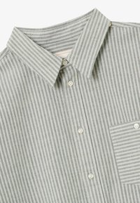 Grau- und weiß gestreifte Hemdbluse mit Kragen und einer Brusttasche auf der linken Seite.