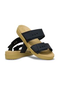 Sandalias de plástico negras con dos correas anchas y una suela acolchada amarilla. El diseño cuenta con una estructura ligera y una planta texturizada.