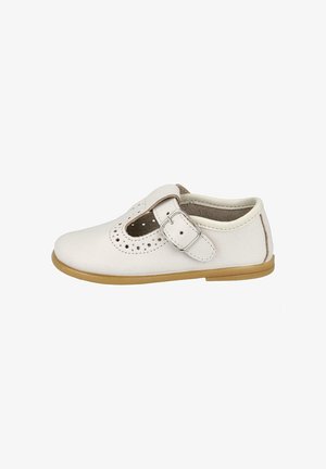 Zapato infantil de cuero blanco con detalles perforados y una correa con hebilla plateada, suela marrón clara y forro interior acolchado.