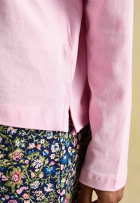 Light pink long-sleeve top with a side slit, paired with a navy floral print skirt featuring pink, green, and blue details. Soft cotton texture.