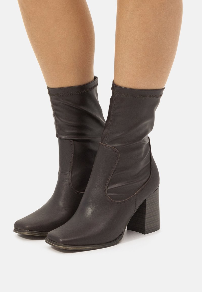 Braune Leder-Ankle-Boots mit lässigem Schaft, quadratischer Spitze und Blockabsatz mit Holztextur. Glatte Oberfläche mit feinen Nähten.