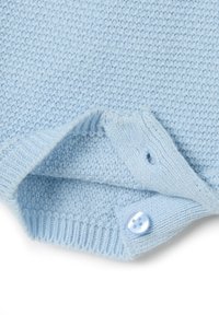 Suéter de punto azul claro con un tejido texturizado, que presenta un dobladillo acanalado y un detalle de botón azul en el cuello.