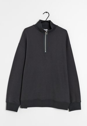 Dunkelgrauer Langarm-Pullover mit einem Frontreißverschluss bis zur Viertellänge und hohem Kragen, präsentiert auf einem schwarzen Kleiderbügel vor weißem Hintergrund.