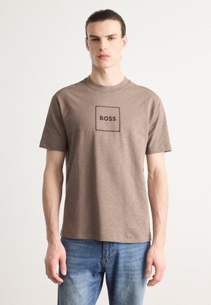 Brown cotton t-shirt with short sleeves and a round neckline, featuring a square logo with "BOSS" printed in black at the center.