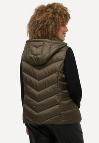 Hedvábná bezrukávová vesta v olivově zelené barvě, s chevronovým prošíváním, vyrobená z hladkého, voděodolného materiálu.